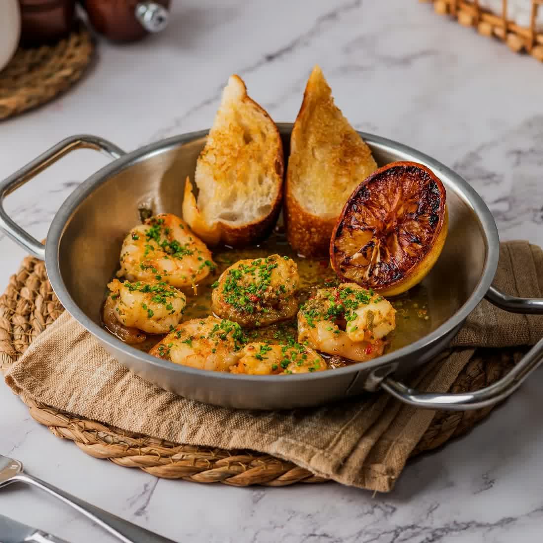 A baked dish served in a pan with charred bread