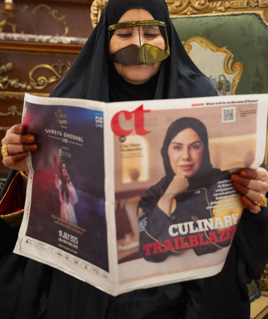 Chef Mariam holding the Culinary Trailblazer newspaper feature