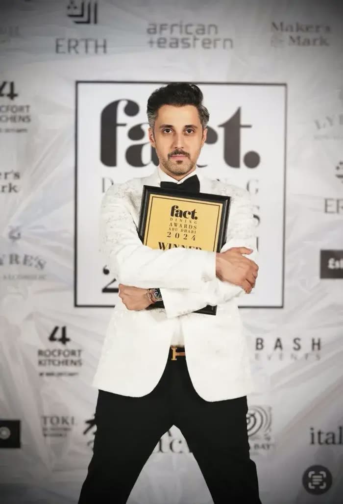 Mohammed Fadhel Al Asfoor in a white dinner jacket holding the Fact Dining Awards 2024 winner plaque