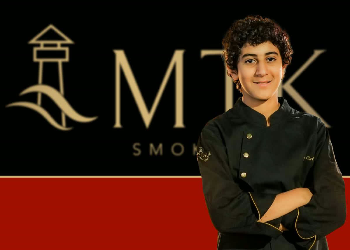 Chef Fadel in Montauk chef whites beside the MTK Smoke House lighthouse mark
